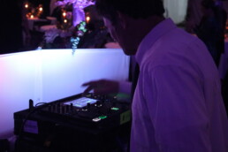 A professional Vermont wedding DJ in a dress shirt fine-tunes a digital mixing console to ensure the perfect soundtrack for your celebration.