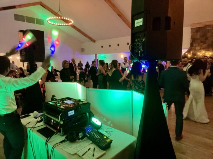 Celebrate your Vermont wedding with a vibrant DJ booth, dancing guests, glowing batons, and colorful lights that energize the night.