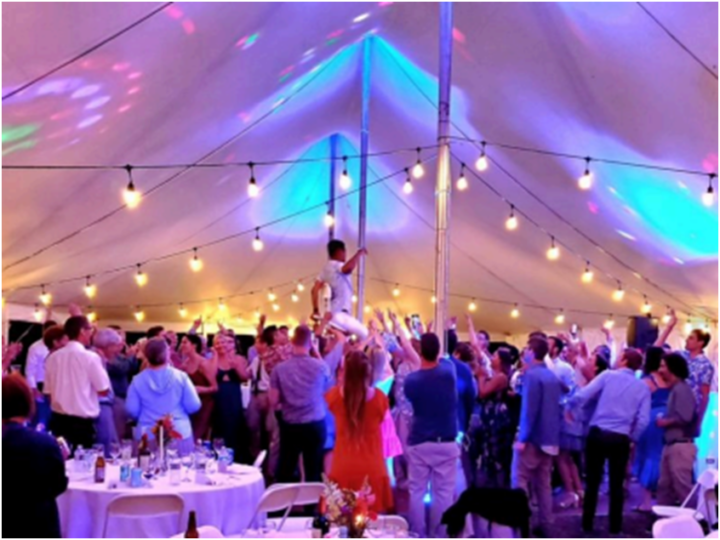 Guests dance joyfully under string lights as a Vermont wedding DJ sets the mood, with vibrant moments and an excited crowd.
