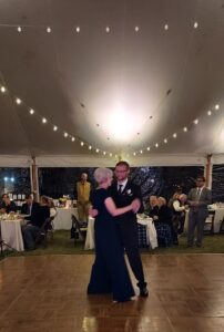 A joyful couple dances under string lights at a tented Vermont wedding, as their DJ’s music creates the perfect romantic atmosphere.